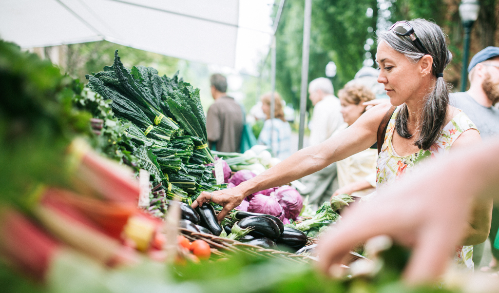 woman selecting produce at an outdoor market