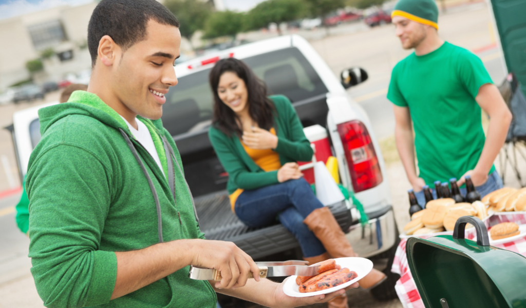 People cooking at a tailgate.