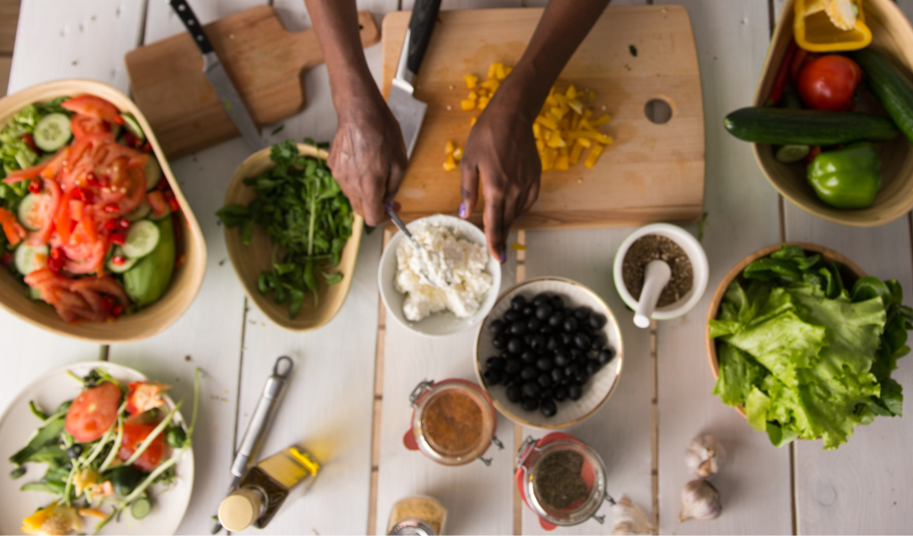 Hands mixing a salad with lettuce and fresh ingredients around
