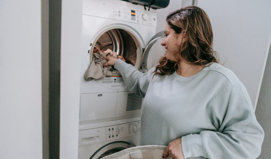 A woman placing laundry in a washing machine.
