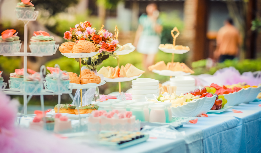 Outdoor table with various food items including cupcakes
