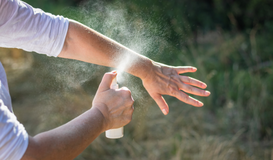 A person spraying bug repellent on arm.