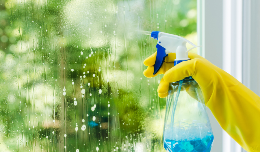 Spray bottle in a hand cleaning a window