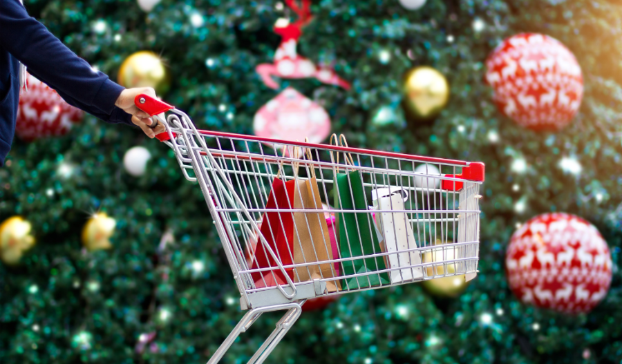 A shopping cart of gifts in front of holiday decorations