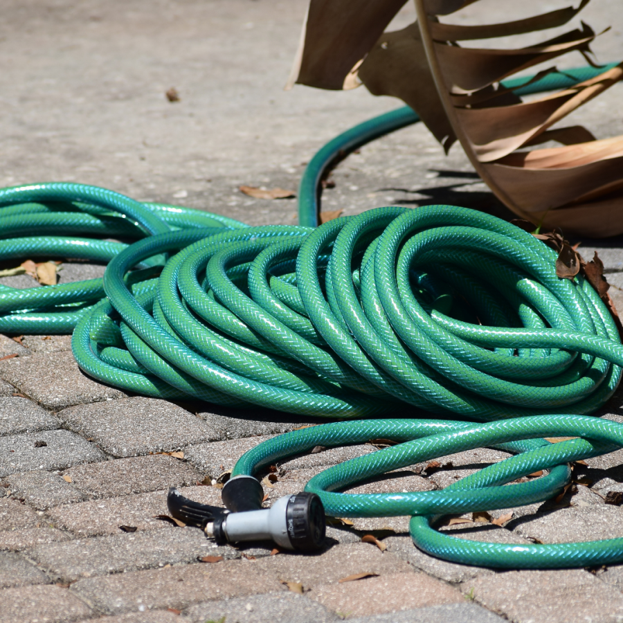 Garden hose in a pile on the ground.