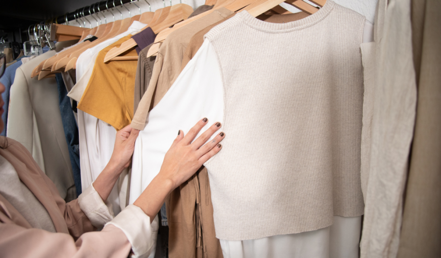 A person touching clothing in a closet