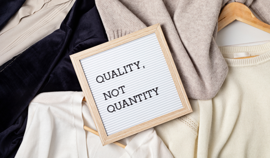 Sign laying over clothes that says "Quality not quantity"