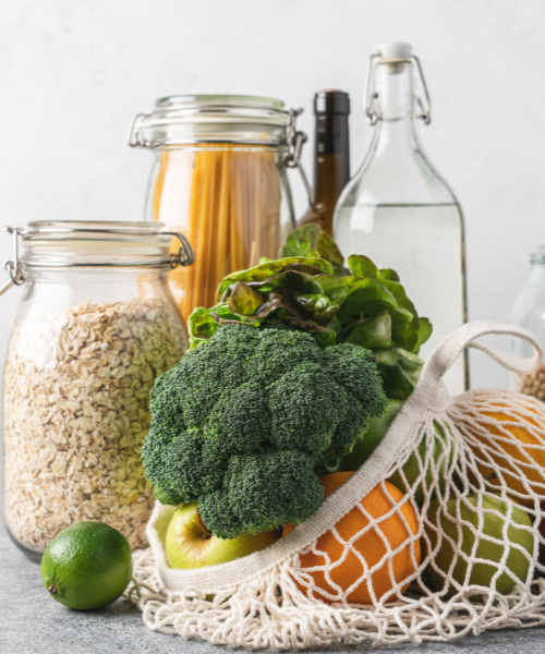 Produce in reusable shopping bag and food in glass containers.
