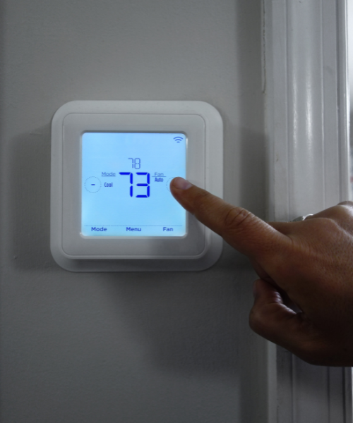 Person adjusting thermostat temperature.