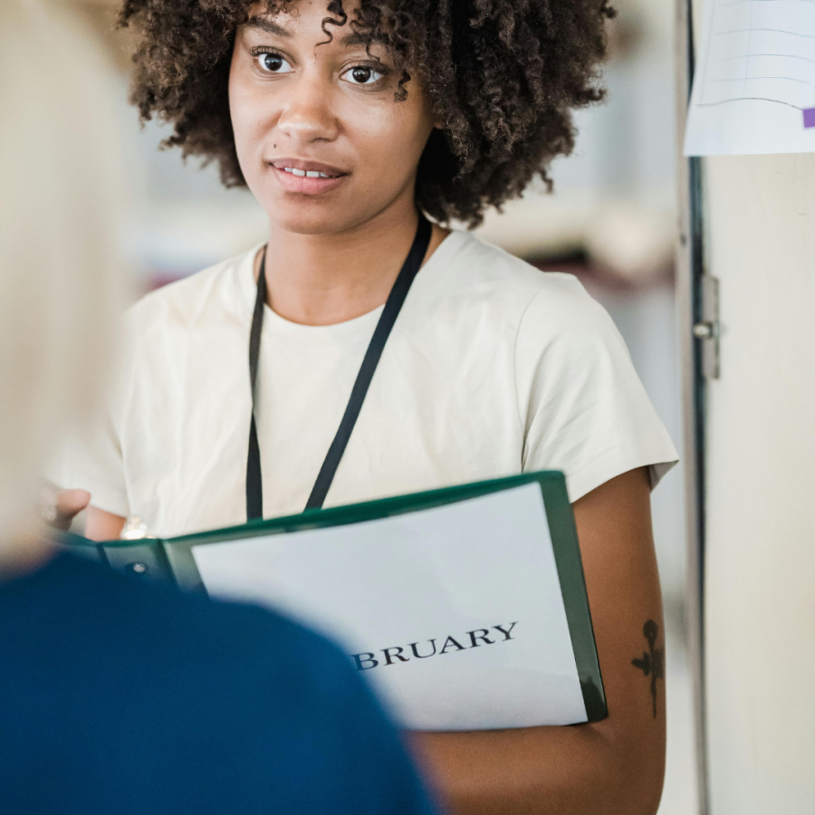 a woman holds a binder while in a meeting 