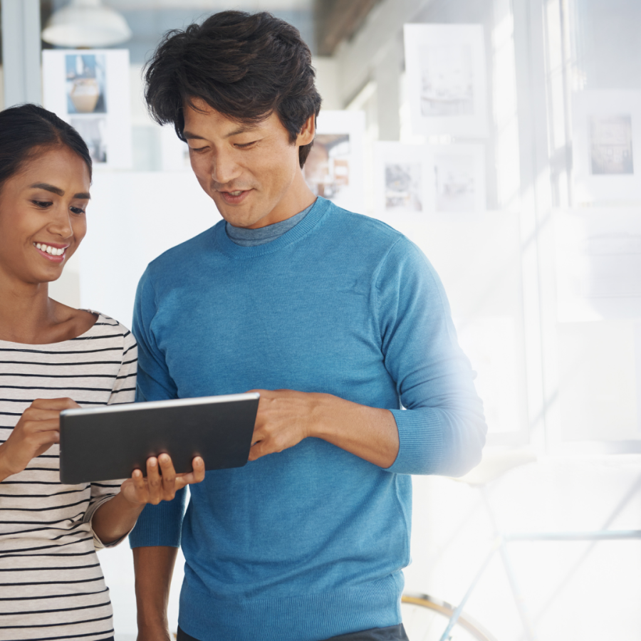 a female and male coworker review office data on a tablet 