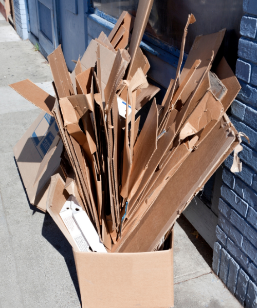 Flattened cardboard boxes in a box on the sidewalk.