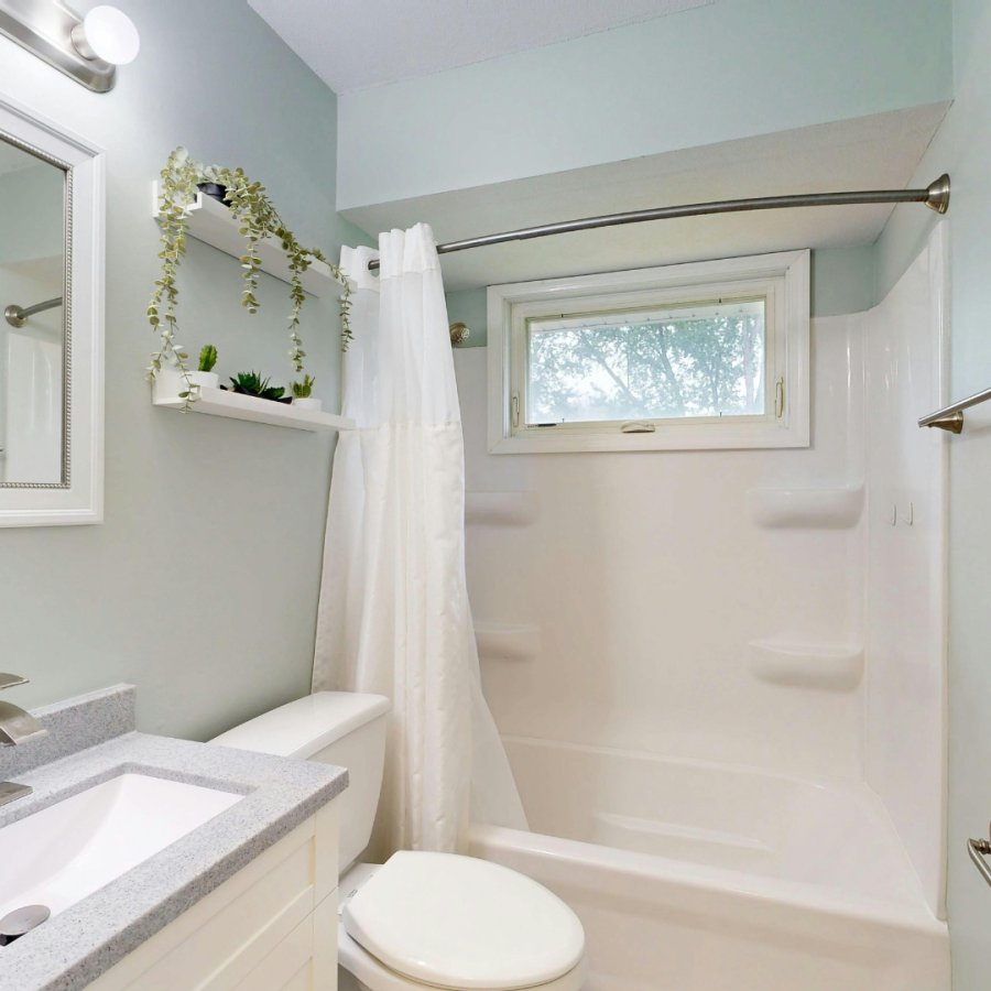 a clean full bathroom with small window 