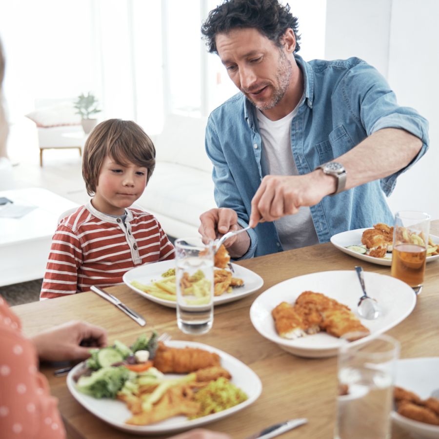 a dad helps his son at the dinner table 