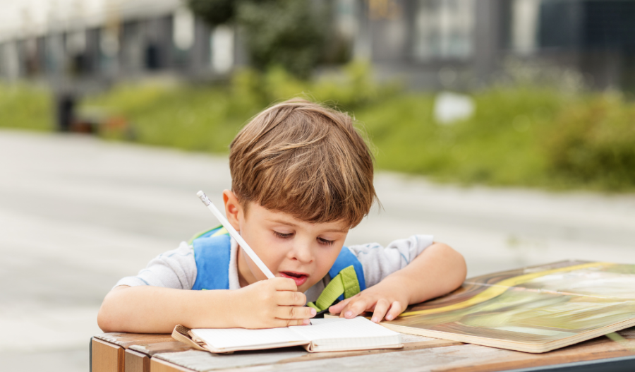 Student writing in journal outside.