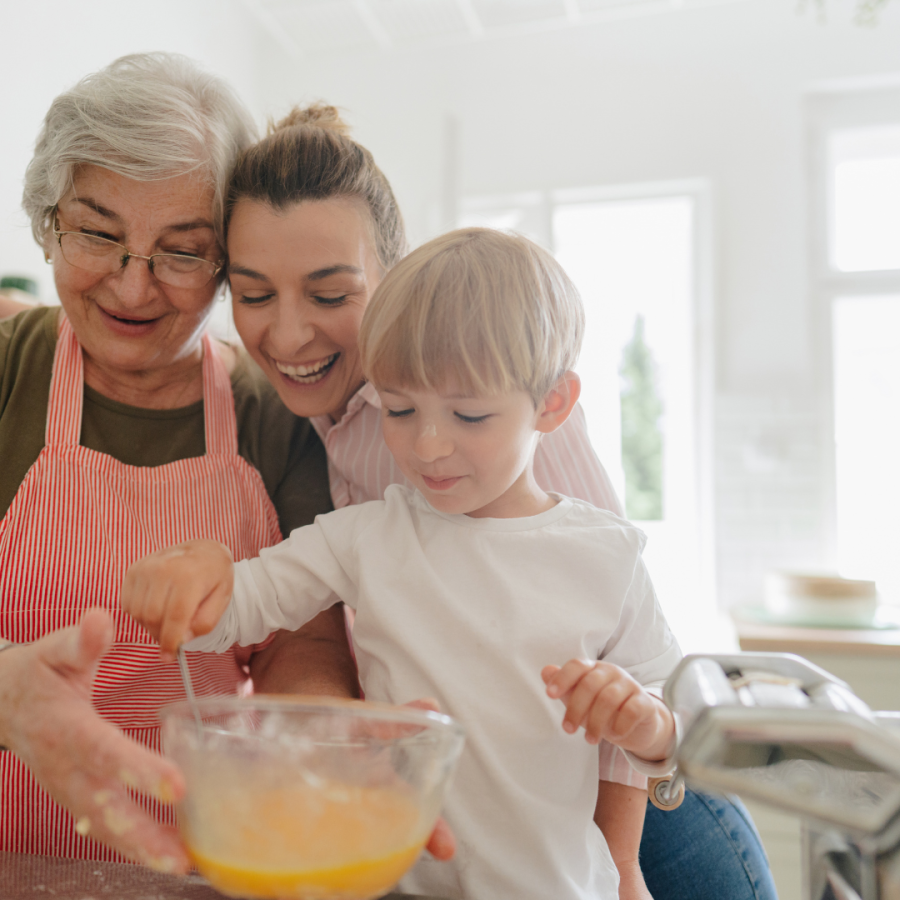 A grandma, daughter and grandson cook in the kitchen.