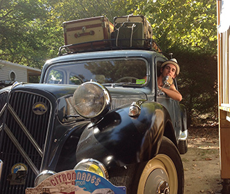 man leaning out of vintage car with roof luggage