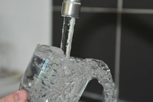 water pouring into glass from faucet